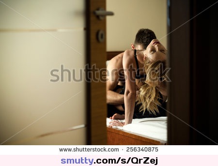 View through the door of young caught couple during foreplay